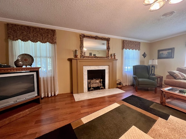 living area featuring visible vents, crown molding, a fireplace, wood finished floors, and a textured ceiling