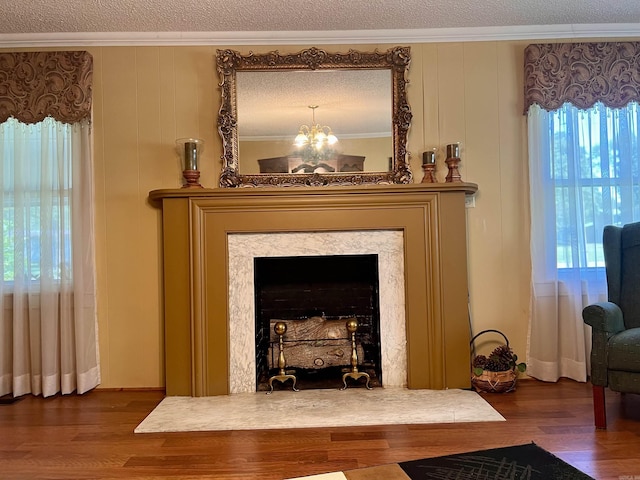 interior details featuring a textured ceiling, an inviting chandelier, wood finished floors, and crown molding