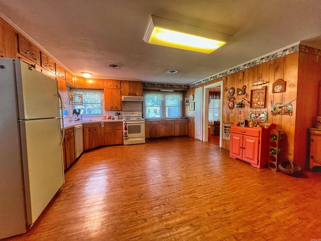 kitchen featuring white appliances, wood finished floors, visible vents, and under cabinet range hood