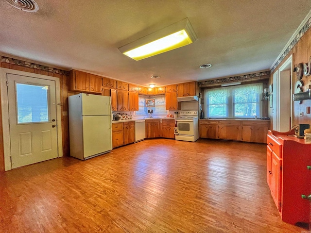 kitchen featuring visible vents, light countertops, light wood-type flooring, brown cabinetry, and white appliances