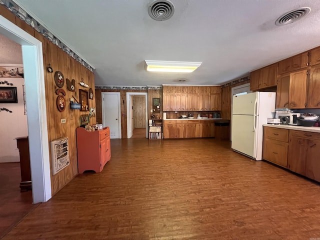 kitchen featuring heating unit, brown cabinetry, visible vents, dark wood finished floors, and freestanding refrigerator