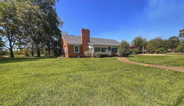 exterior space featuring a yard, brick siding, and a chimney