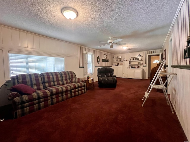 living room featuring dark colored carpet, a textured ceiling, and a ceiling fan