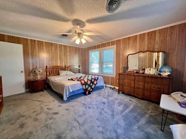 carpeted bedroom featuring a ceiling fan, wooden walls, crown molding, and a textured ceiling