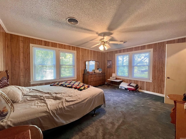 carpeted bedroom with visible vents, a textured ceiling, crown molding, and wooden walls