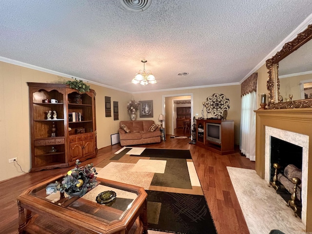 living room featuring visible vents, crown molding, a premium fireplace, an inviting chandelier, and wood finished floors
