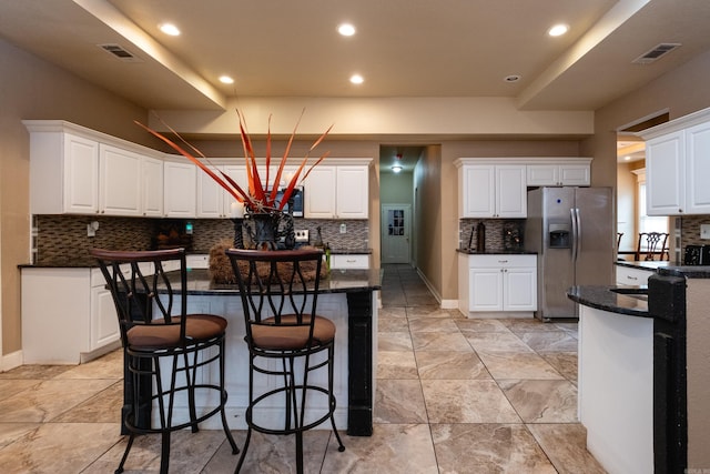 kitchen featuring white cabinets, a kitchen island, stainless steel fridge with ice dispenser, and decorative backsplash