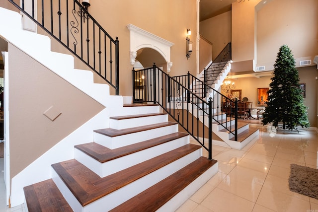 staircase featuring a towering ceiling and tile patterned flooring