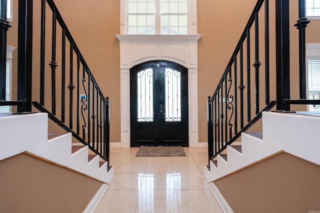 tiled entryway with a wealth of natural light, a high ceiling, and french doors