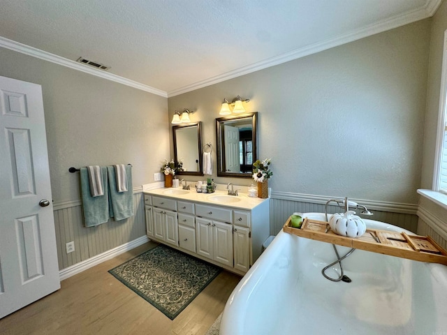 bathroom with hardwood / wood-style flooring, crown molding, a tub to relax in, vanity, and a textured ceiling