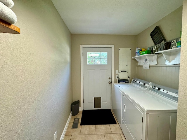 laundry area with separate washer and dryer, a textured ceiling, and light tile patterned floors