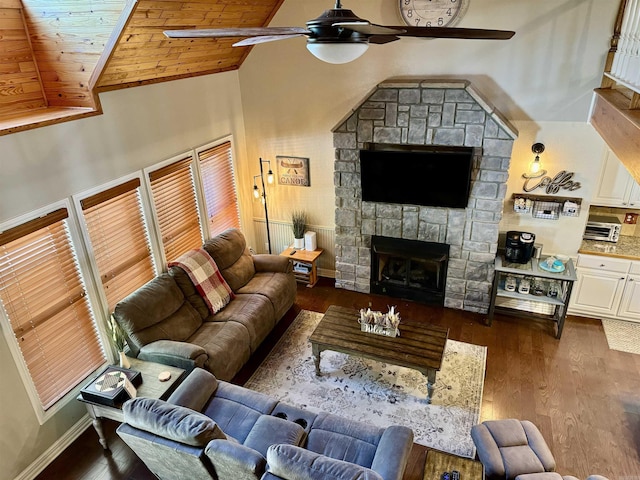 living room featuring wood finished floors, baseboards, a fireplace, ceiling fan, and wooden ceiling