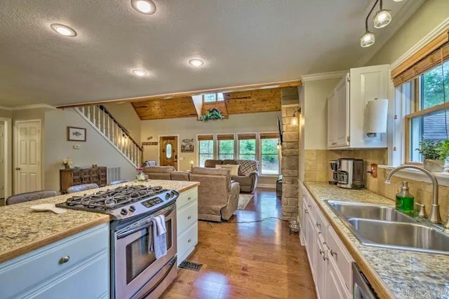 kitchen with a wealth of natural light, stainless steel gas stove, and white cabinetry