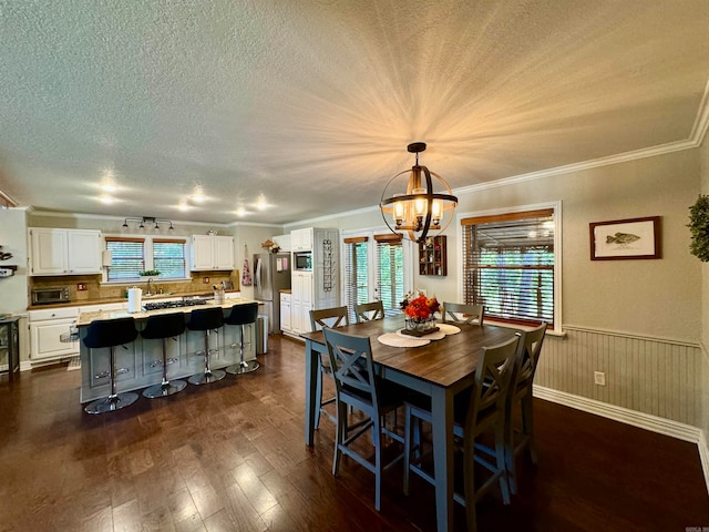 dining area with dark wood-type flooring, crown molding, a notable chandelier, and a textured ceiling