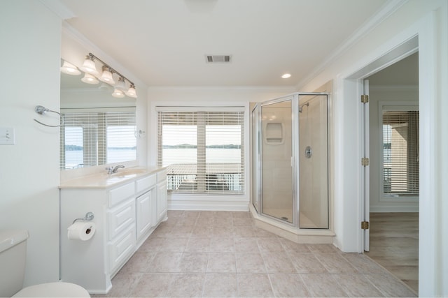 bathroom featuring a shower with door, vanity, toilet, and ornamental molding