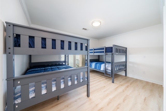 bedroom featuring ornamental molding and light hardwood / wood-style flooring