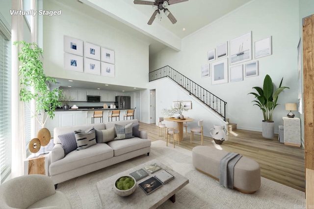 living room with light wood-type flooring, ceiling fan, beam ceiling, and a towering ceiling