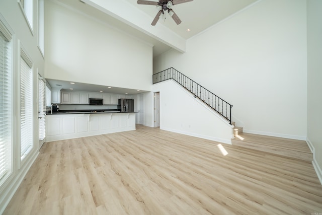 unfurnished living room featuring high vaulted ceiling, sink, wood-type flooring, and ceiling fan