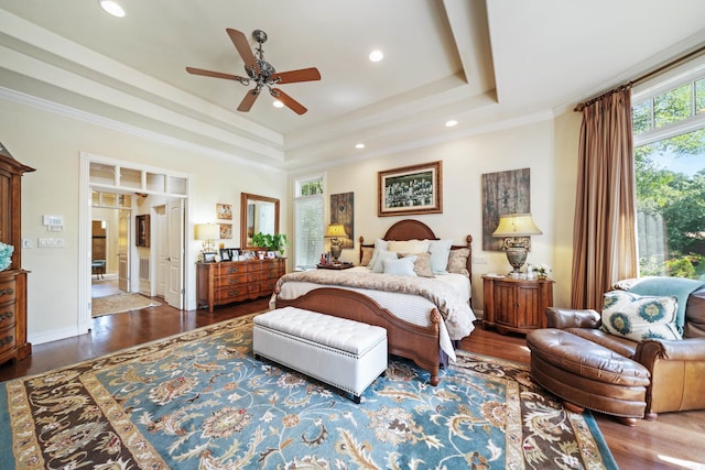 bedroom with a tray ceiling, dark hardwood / wood-style flooring, ornamental molding, and ceiling fan