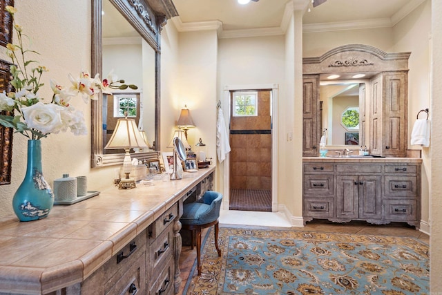 bathroom with tile patterned flooring, vanity, ornamental molding, and a tile shower