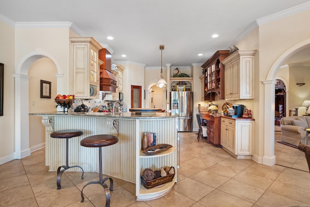 kitchen with pendant lighting, kitchen peninsula, cream cabinets, stainless steel fridge with ice dispenser, and stone countertops