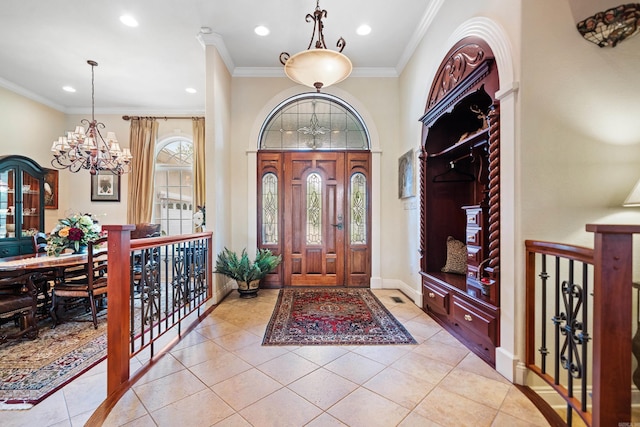 entryway featuring ornamental molding, an inviting chandelier, and light tile patterned flooring