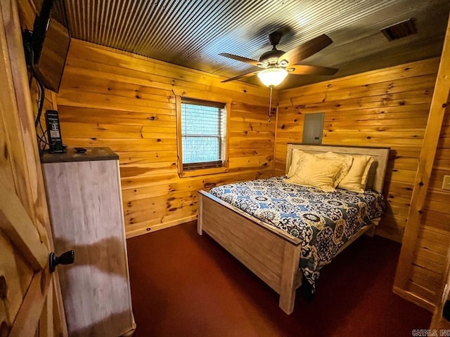 bedroom with dark carpet, ceiling fan, and wooden walls