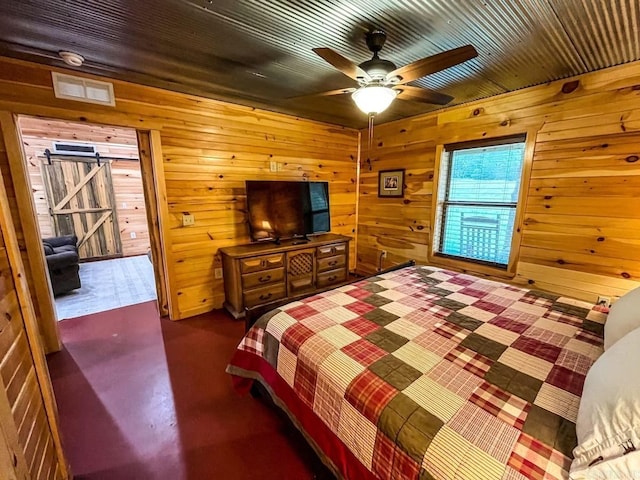 bedroom with a barn door, ceiling fan, and wood walls