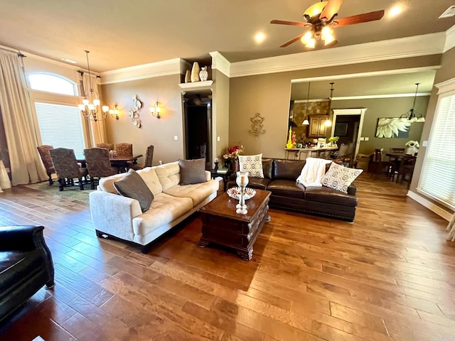 living room featuring ornamental molding, hardwood / wood-style flooring, and ceiling fan with notable chandelier