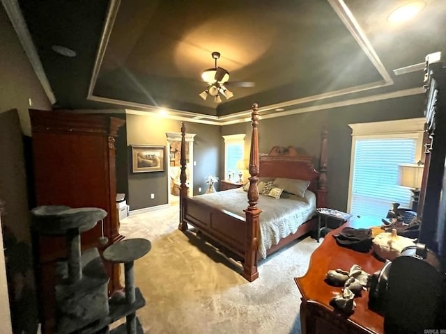 bedroom with ceiling fan, light carpet, a tray ceiling, and crown molding