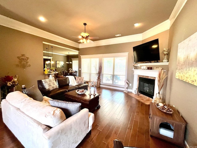 living room with a tiled fireplace, crown molding, dark hardwood / wood-style floors, and ceiling fan