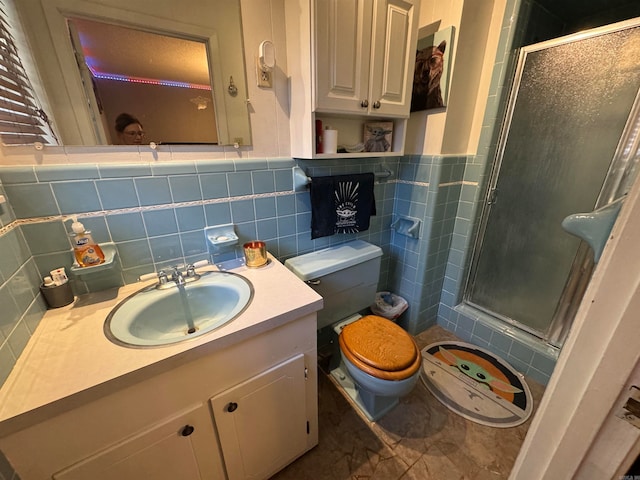 bathroom featuring a shower with door, vanity, tasteful backsplash, tile walls, and toilet