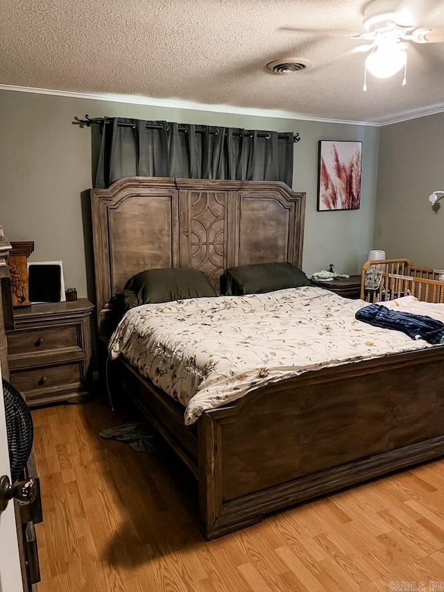 bedroom featuring a textured ceiling, crown molding, ceiling fan, and light hardwood / wood-style floors