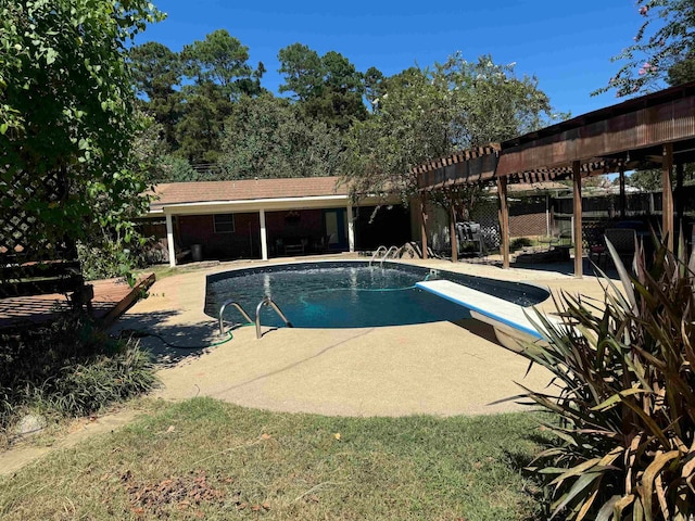 view of swimming pool with a diving board and a patio