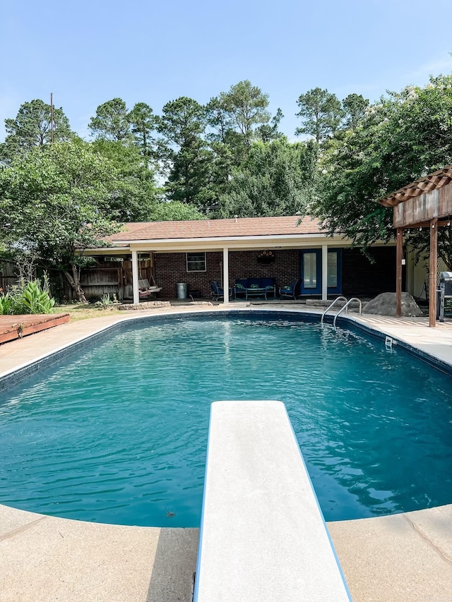 view of swimming pool with a patio area and a diving board