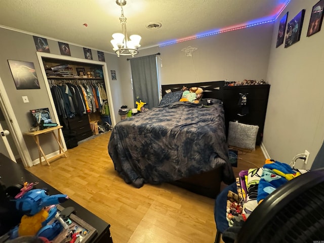 bedroom with a closet, a chandelier, a textured ceiling, and light hardwood / wood-style flooring