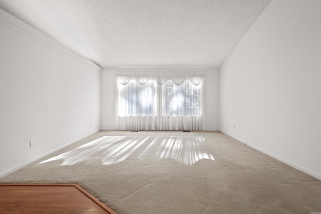 carpeted empty room featuring baseboards and a textured ceiling