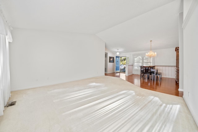 living area featuring visible vents, wood finished floors, an inviting chandelier, wainscoting, and vaulted ceiling