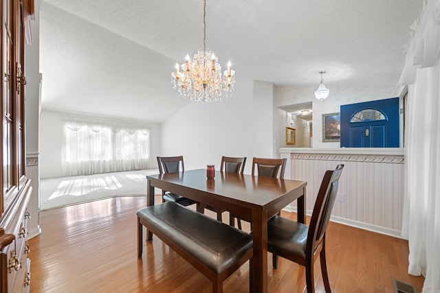 dining room featuring a textured ceiling, wood finished floors, and vaulted ceiling