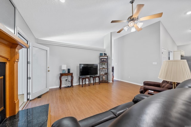 living area with a ceiling fan, vaulted ceiling, wood finished floors, and baseboards