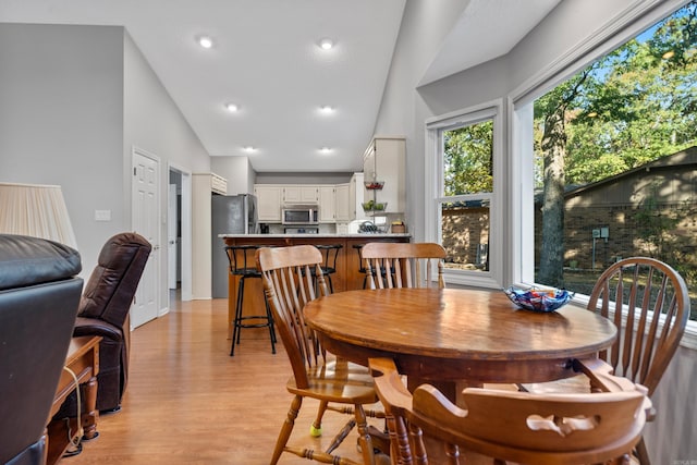 dining room with recessed lighting, lofted ceiling, and light wood-style floors