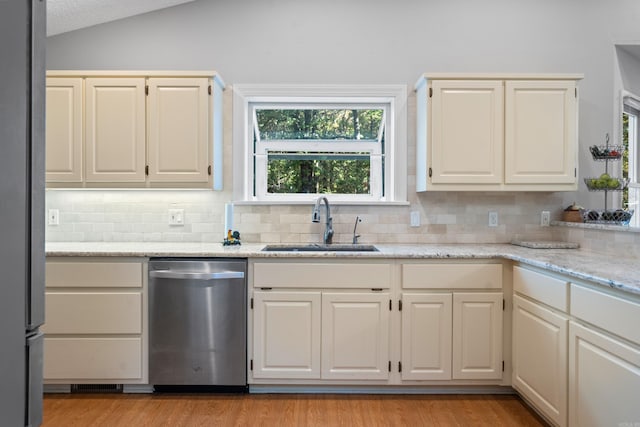 kitchen featuring a sink, stainless steel appliances, light wood finished floors, decorative backsplash, and lofted ceiling