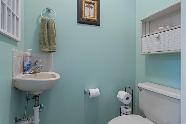 bathroom with a sink, decorative backsplash, and toilet