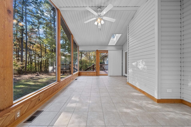 unfurnished sunroom featuring a skylight, visible vents, and ceiling fan