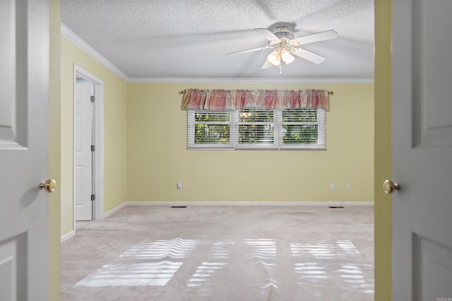 carpeted spare room featuring baseboards, a textured ceiling, a ceiling fan, and ornamental molding