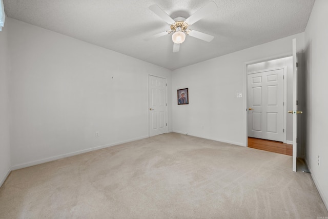 empty room with light carpet, baseboards, a textured ceiling, and a ceiling fan