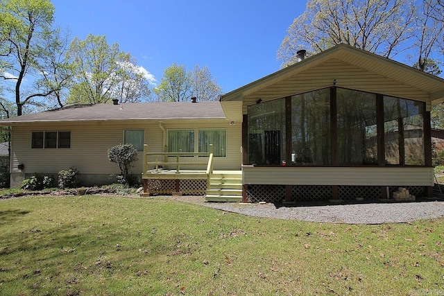 rear view of house with a yard, a wooden deck, and a sunroom