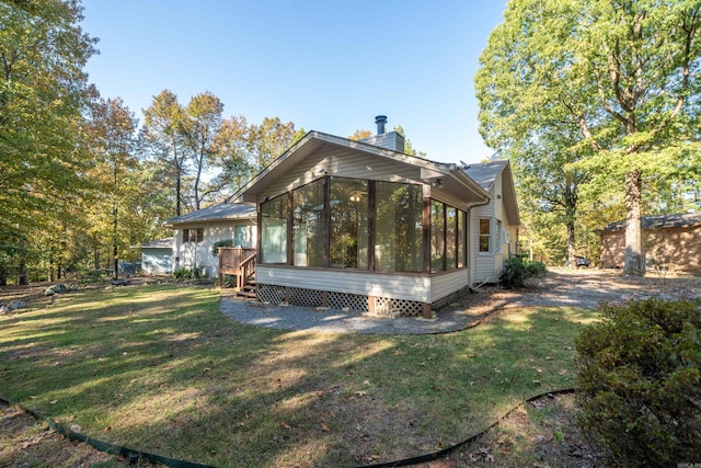 back of property featuring a yard, a chimney, and a sunroom