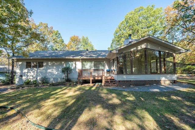 back of property with a yard, a chimney, a sunroom, and a wooden deck