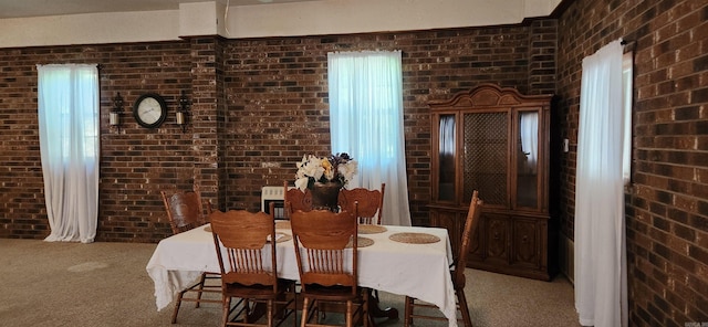 dining area featuring brick wall and carpet flooring